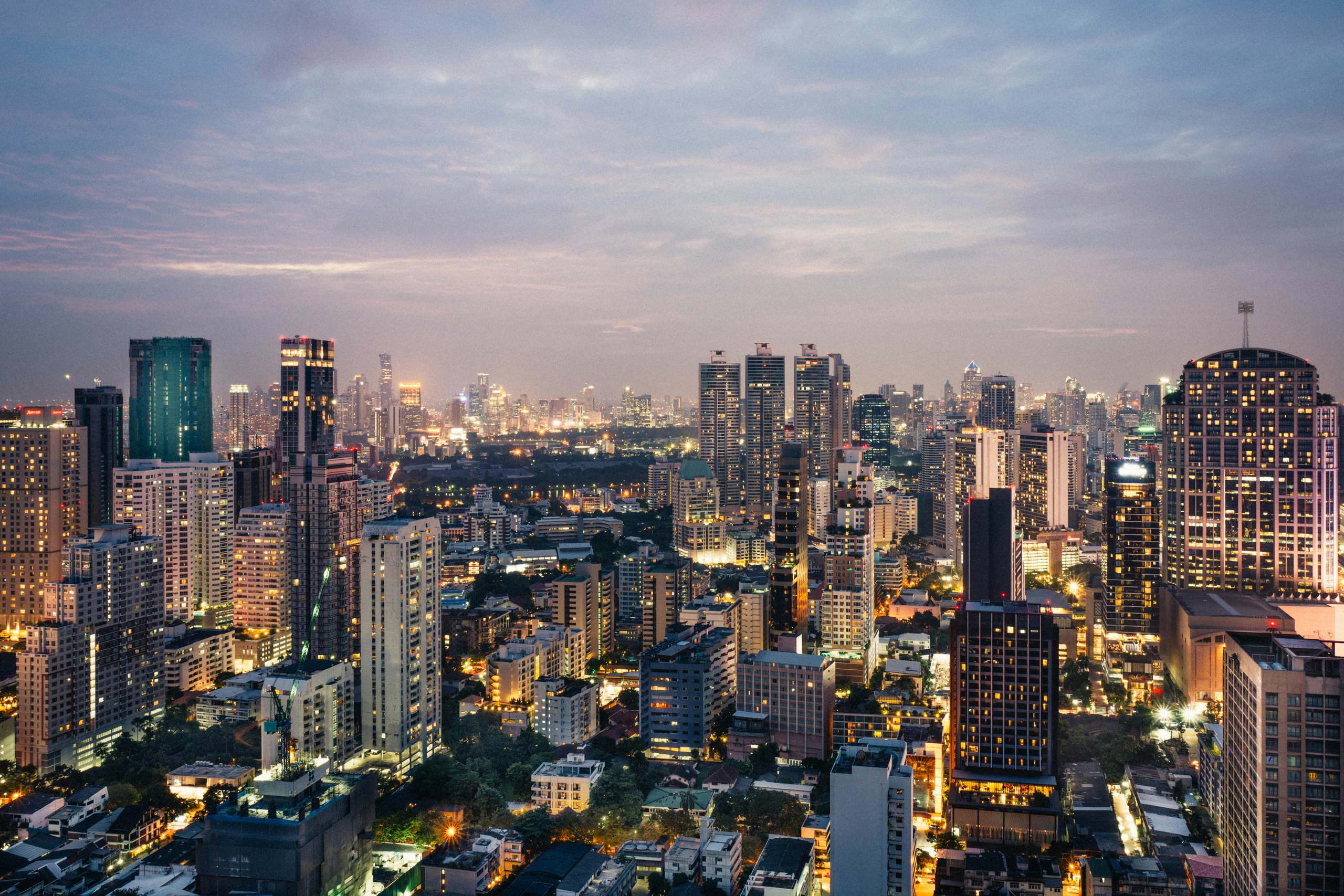 Bangkok skyline at dusk, with city lights coming on across the business district