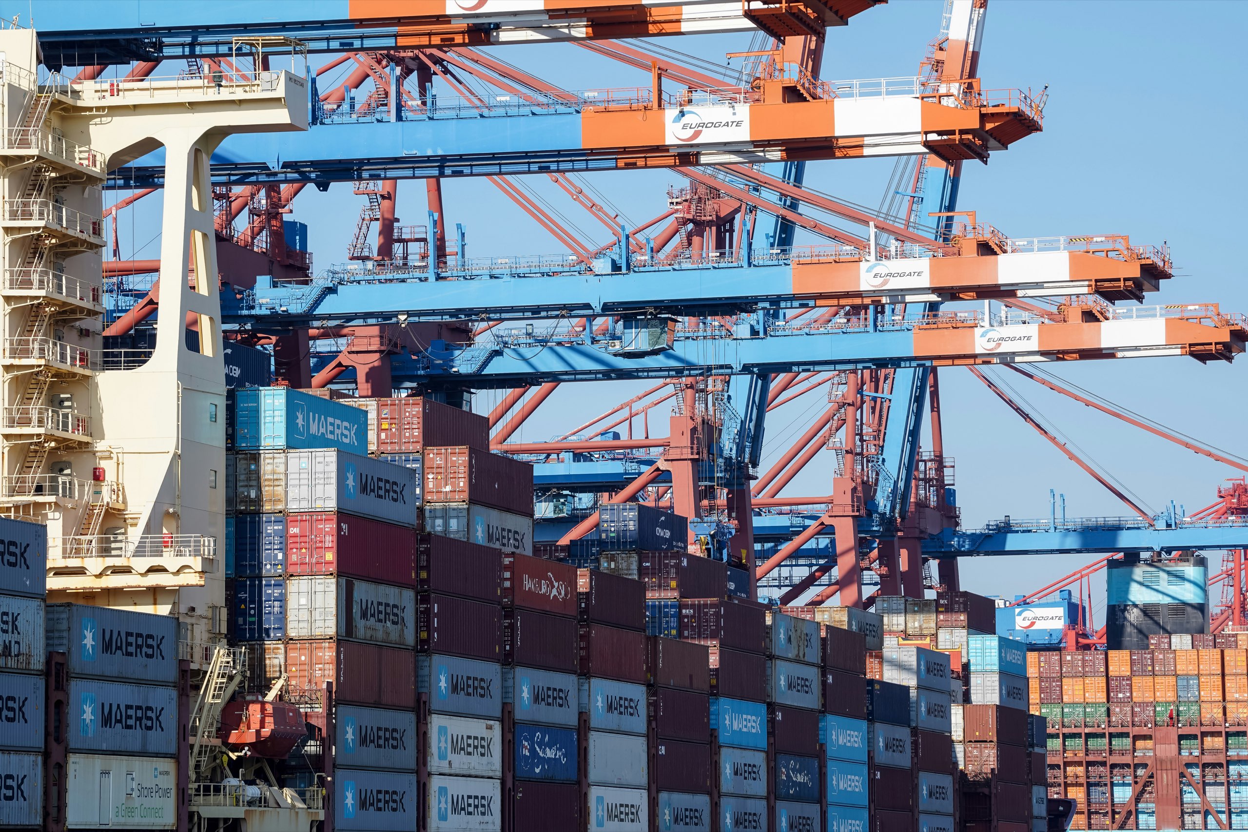 Container cranes working above stacked cargo containers at a port