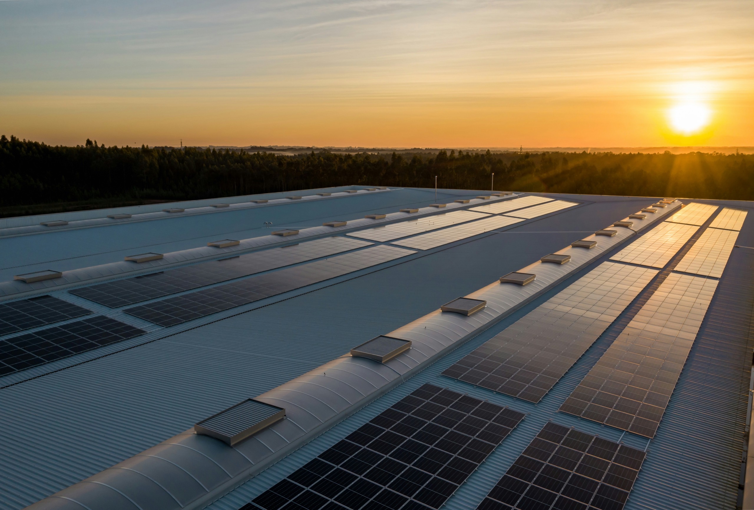 Solar panels on the roof of a large factory building at sunset