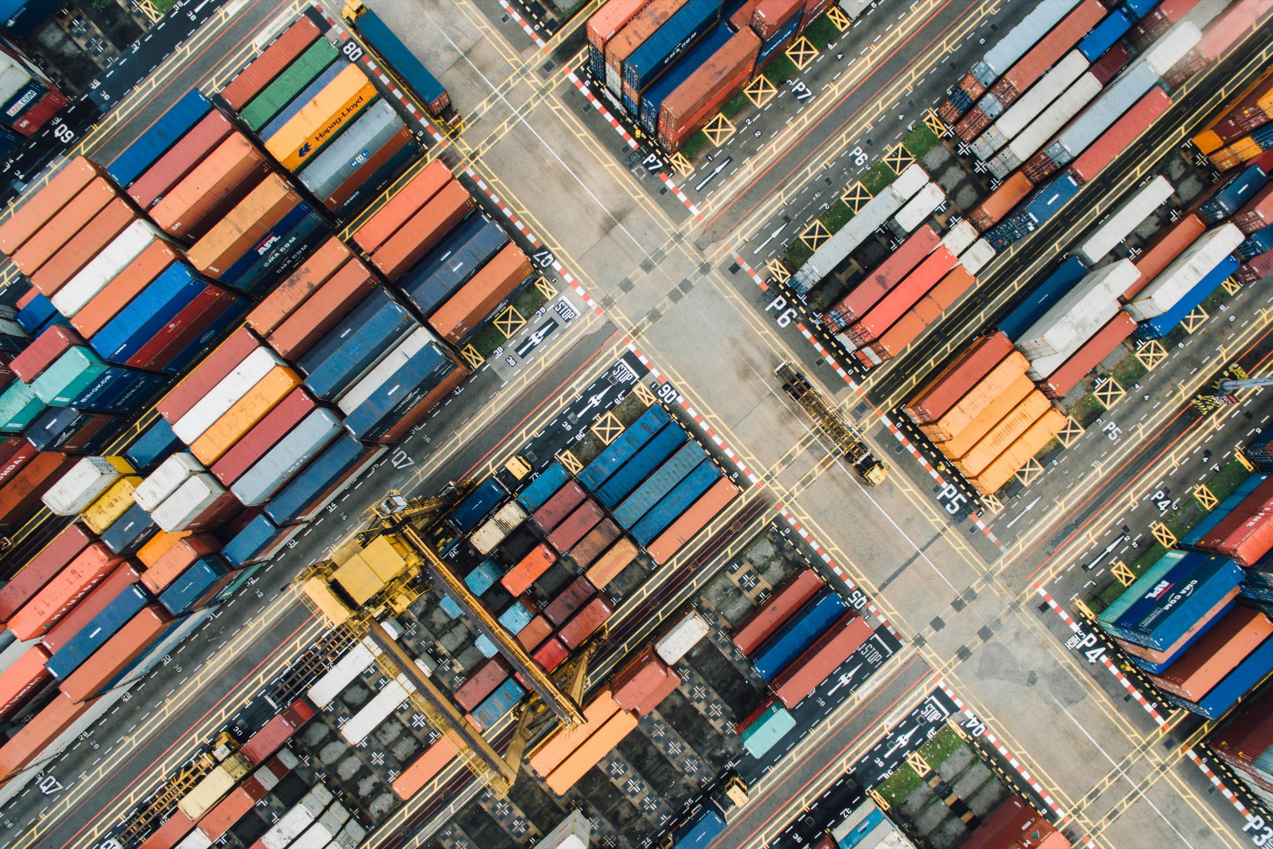 Shipping containers stacked in rows at a port terminal, seen from directly above
