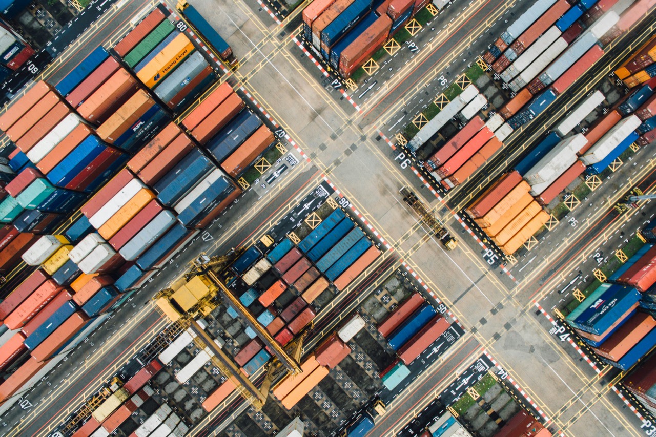 Shipping containers stacked in rows at a port terminal, seen from directly above