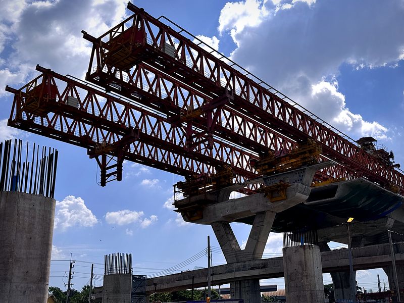 Two red truss launching gantries on an elevated road in Thailand